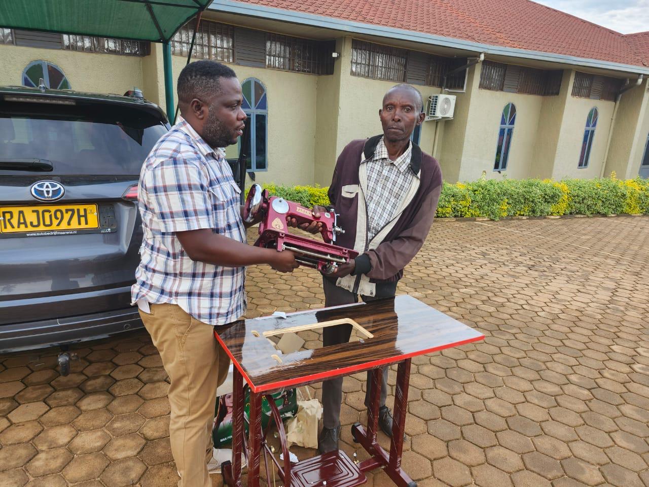 ASEDC staff presenting a sewing machine to a program graduate